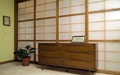 A wall of fixed Japanese shoji screens with one sliding door at the top of the stairs.