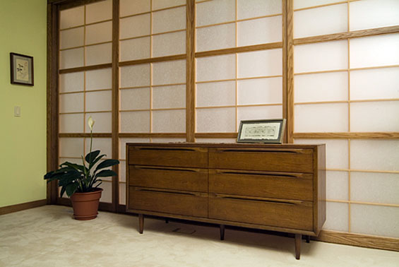 A wall of fixed Japanese shoji screens with one sliding door at the top of the stairs.