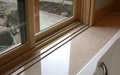 The upper tracking is wood and the lower tracking is a metal strip installed in the marble that engages a groove inlaid into the bottom of the window screen.